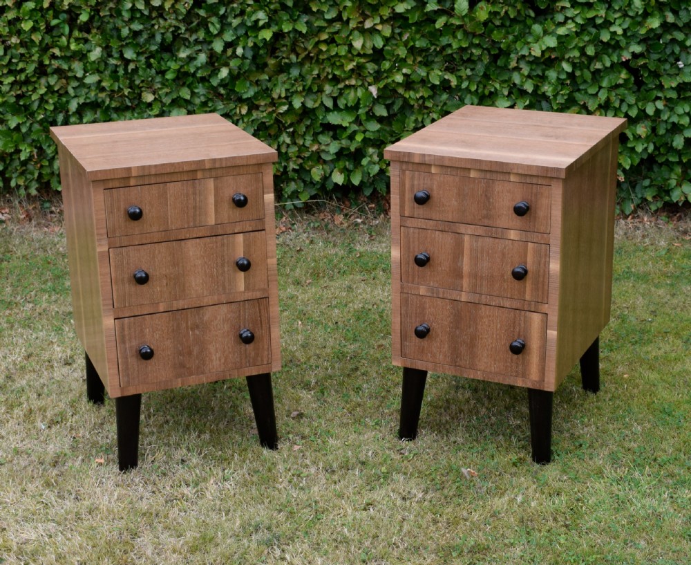 A matching pair of three-drawer walnut bedside chests featuring dark turned knobs and ebonised tapered legs. View XV