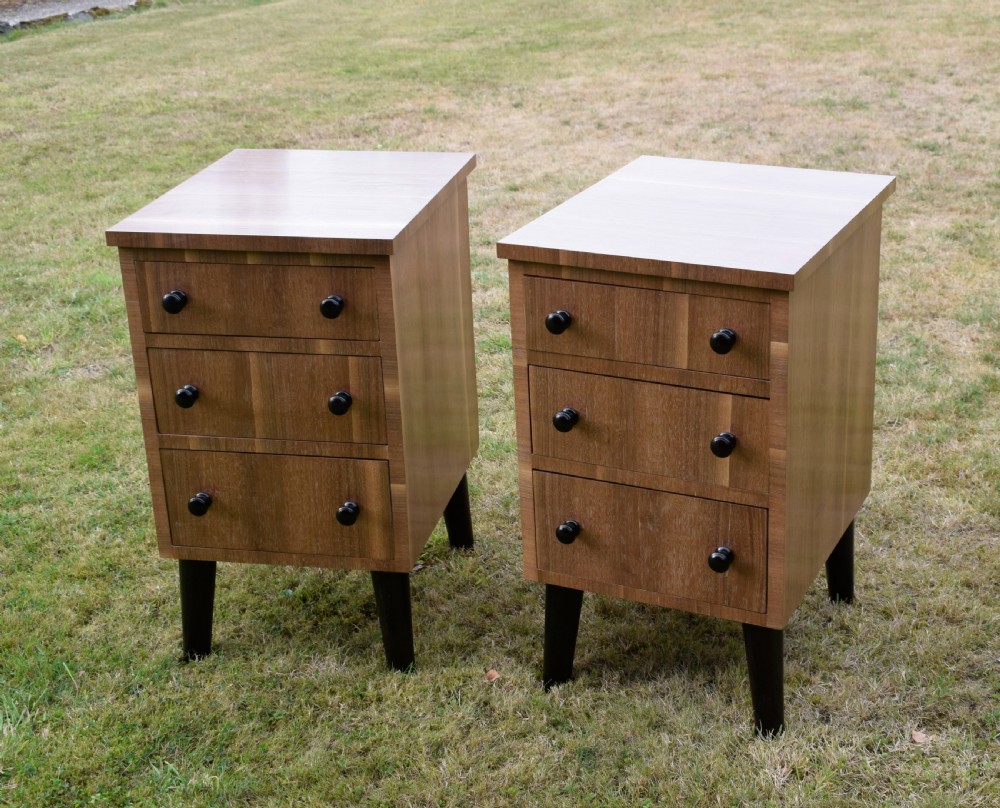 A matching pair of three-drawer walnut bedside chests featuring dark turned knobs and ebonised tapered legs. View XX