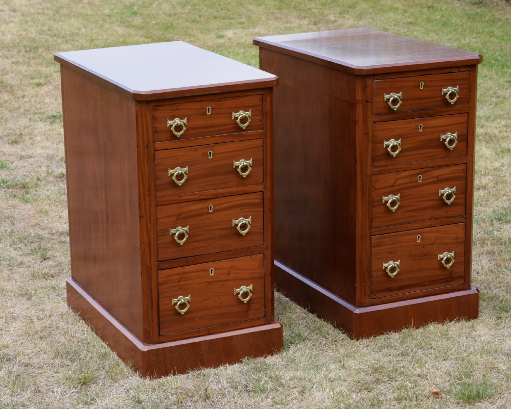 A pair of Victorian mahogany four-drawer bedside chests featuring brass ring handles, escutcheons, and plinth bases.