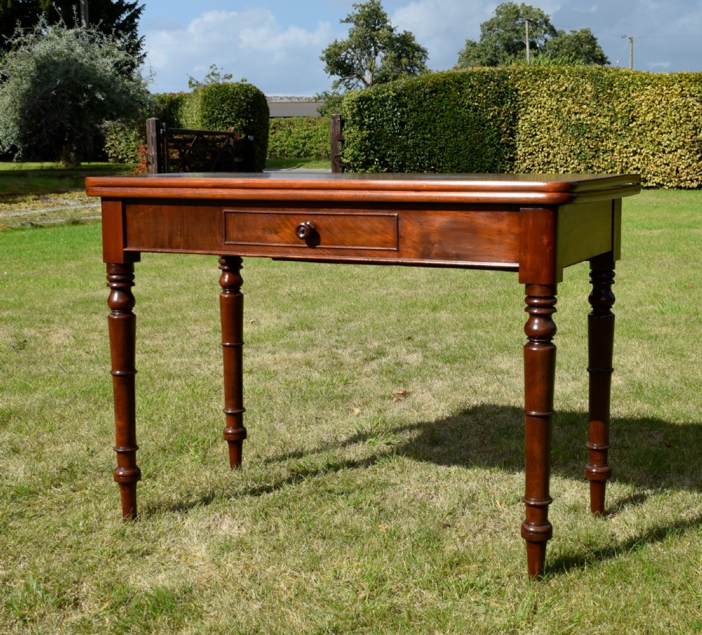 A William IV polished mahogany fold-over games table with turned legs and a single central drawer with a wooden knob. View VI