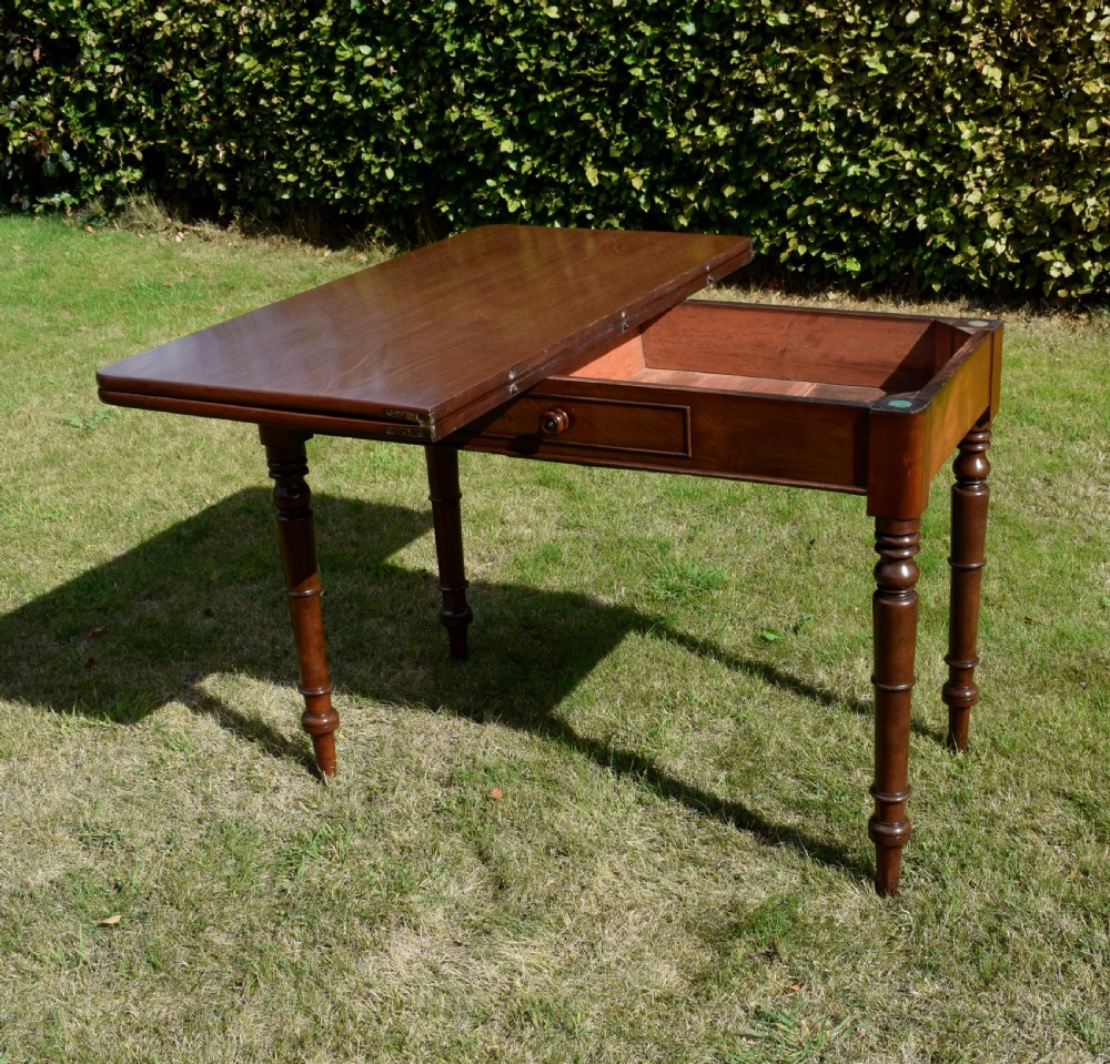 A William IV polished mahogany fold-over games table with turned legs and a single central drawer with a wooden knob. View VII