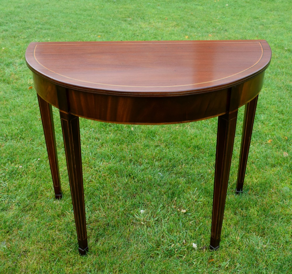 A mahogany demi-lune console table featuring light-coloured string inlay along the top perimeter, apron, and four square tapered legs. View II