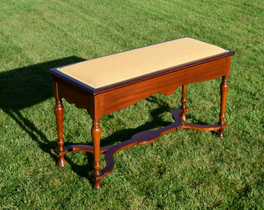 A long mahogany duet stool featuring turned legs, a shaped apron, a central curved cross-stretcher, and a yellow woven upholstered seat. View II