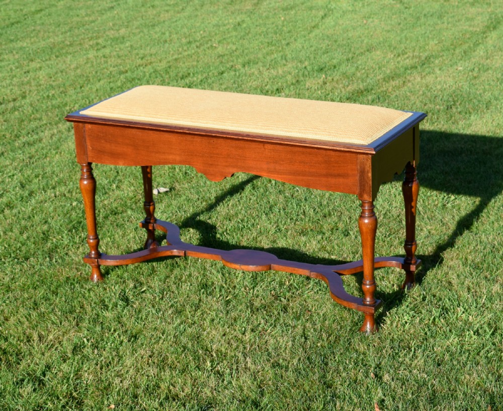 A long mahogany duet stool featuring turned legs, a shaped apron, a central curved cross-stretcher, and a yellow woven upholstered seat. View III