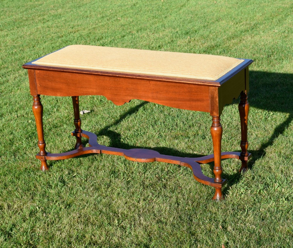A long mahogany duet stool featuring turned legs, a shaped apron, a central curved cross-stretcher, and a yellow woven upholstered seat. View XI