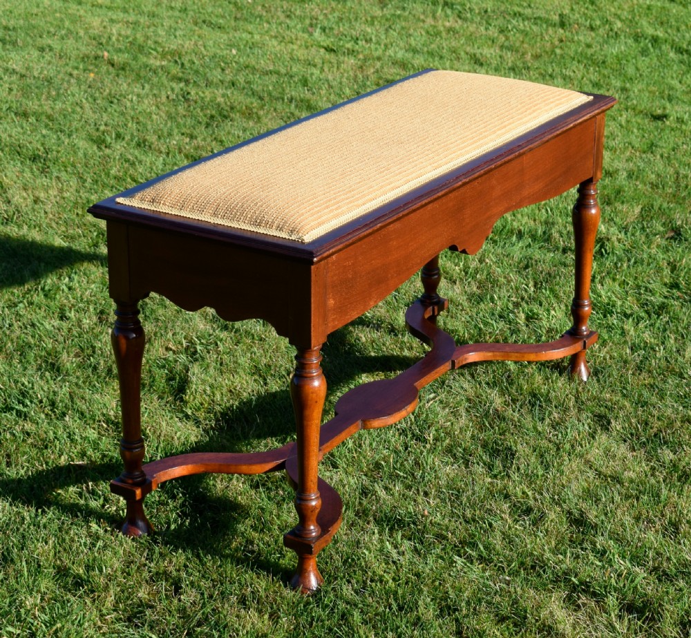 A long mahogany duet stool featuring turned legs, a shaped apron, a central curved cross-stretcher, and a yellow woven upholstered seat. View XII