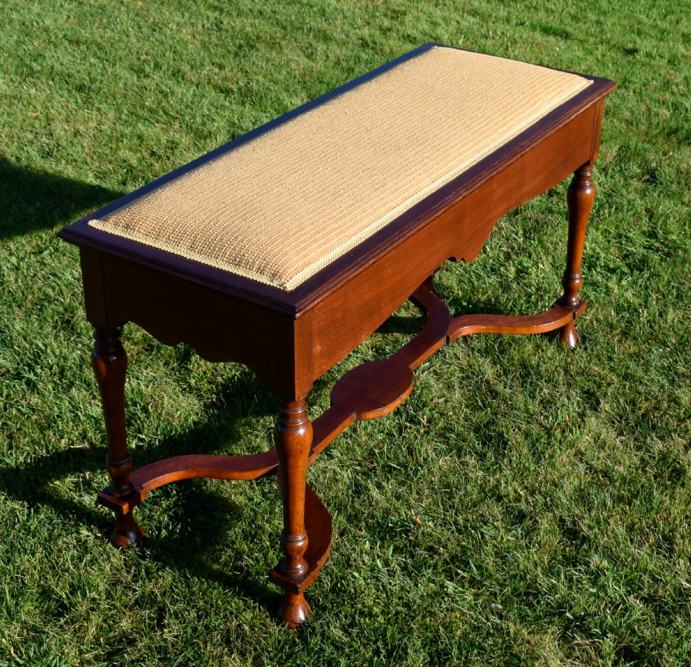 A long mahogany duet stool featuring turned legs, a shaped apron, a central curved cross-stretcher, and a yellow woven upholstered seat. View XIII