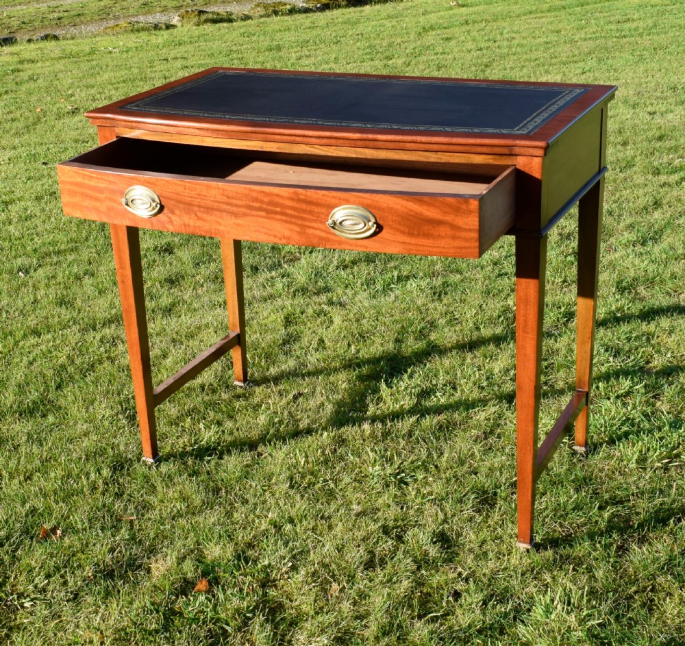 An early twentieth-century mahogany writing table featuring an inset green leather top, a single drawer with two brass oval drop handles, and tapered square legs. View VI