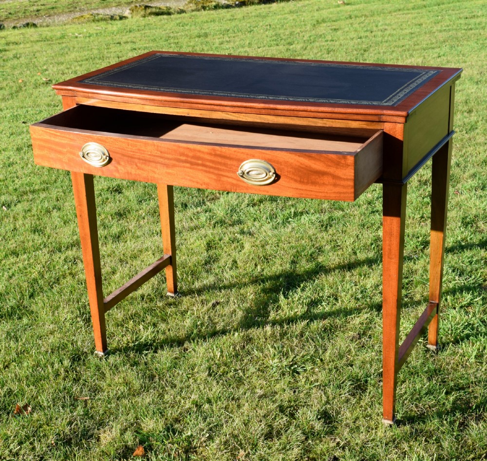 An early twentieth-century mahogany writing table featuring an inset green leather top, a single drawer with two brass oval drop handles, and tapered square legs. View VII
