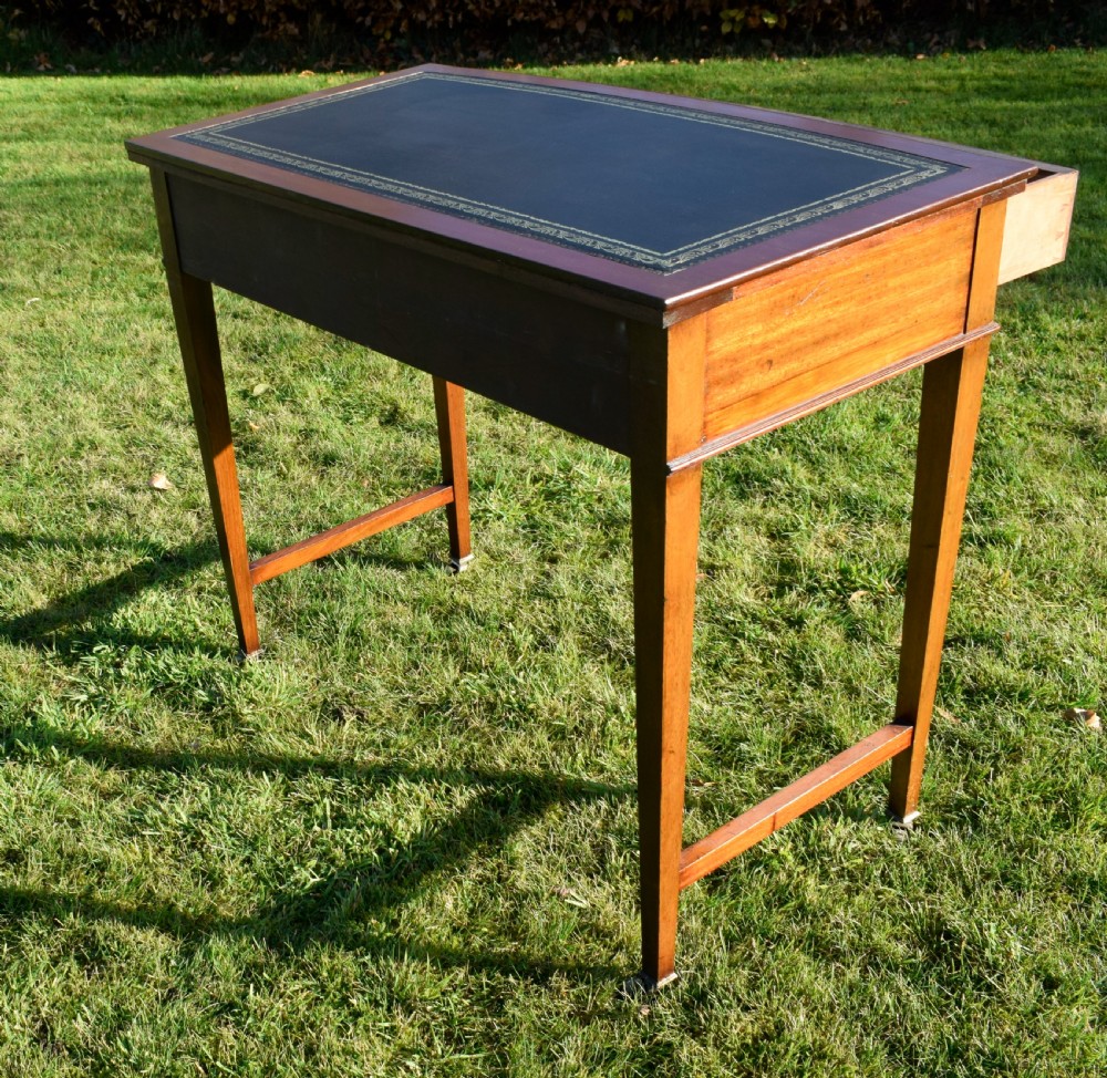 An early twentieth-century mahogany writing table featuring an inset green leather top, a single drawer with two brass oval drop handles, and tapered square legs. View IX