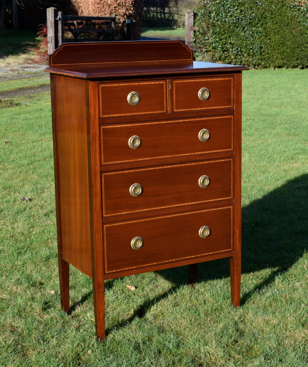 An Edwardian mahogany tall chest of drawers featuring fine string inlay, brass ring handles, five drawers, a low raised backboard, and square tapered legs. View III