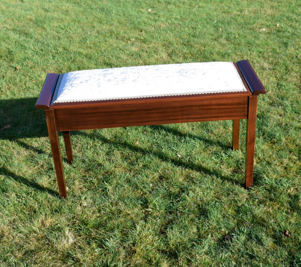 An Art Deco dark mahogany duet piano stool featuring a cushioned pale pink velvet seat with braided gimp trim and straight tapered legs. View IV