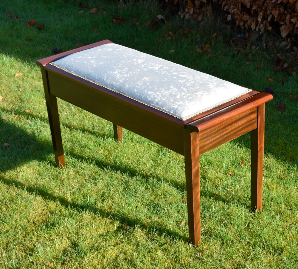 An Art Deco dark mahogany duet piano stool featuring a cushioned pale pink velvet seat with braided gimp trim and straight tapered legs. View VI