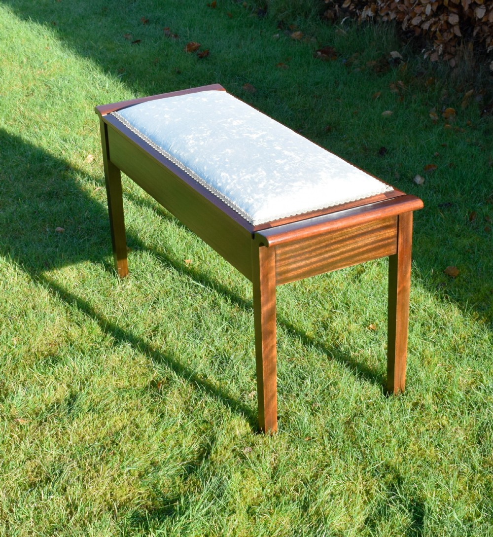 An Art Deco dark mahogany duet piano stool featuring a cushioned pale pink velvet seat with braided gimp trim and straight tapered legs. View IX