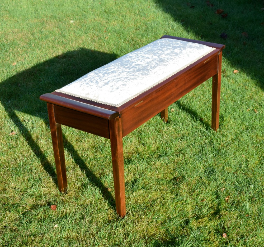 An Art Deco dark mahogany duet piano stool featuring a cushioned pale pink velvet seat with braided gimp trim and straight tapered legs. View XI
