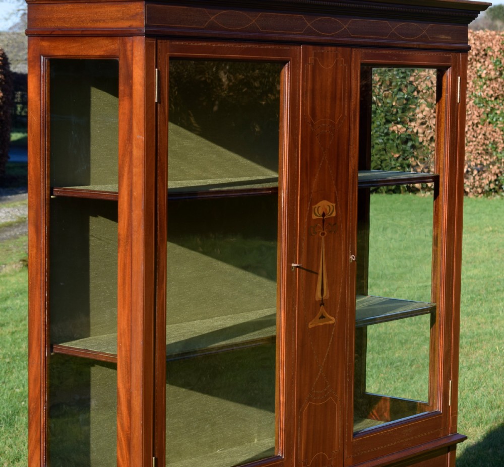 An early 20th-century mahogany Art Nouveau display cabinet featuring glazed doors, central inlaid botanical marquetry, and a fabric-lined interior on slender legs. View III