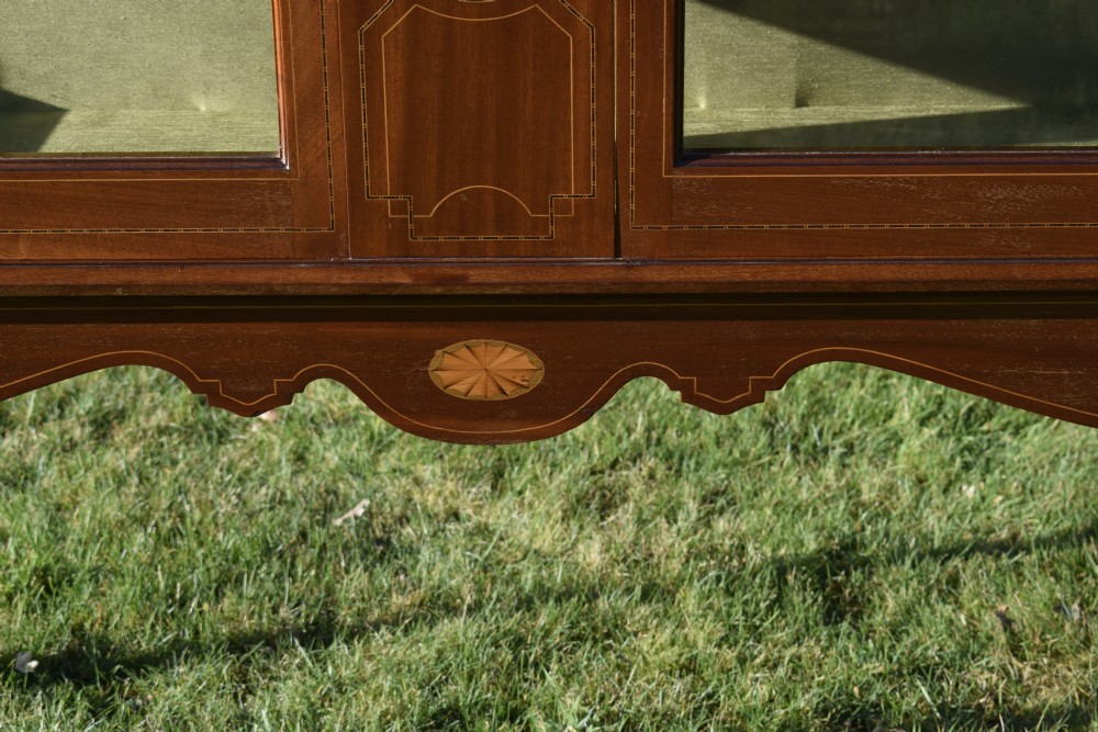 An early 20th-century mahogany Art Nouveau display cabinet featuring glazed doors, central inlaid botanical marquetry, and a fabric-lined interior on slender legs. View VIII