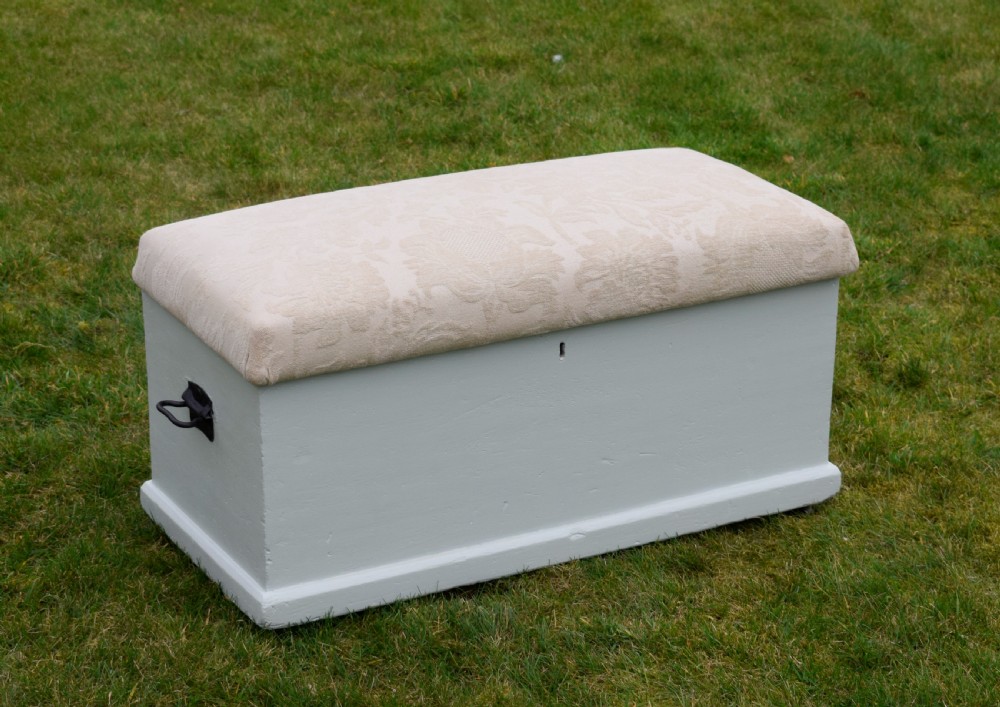 A Victorian painted pine blanket box featuring a cream upholstered cushioned top and iron drop side handles. View VI