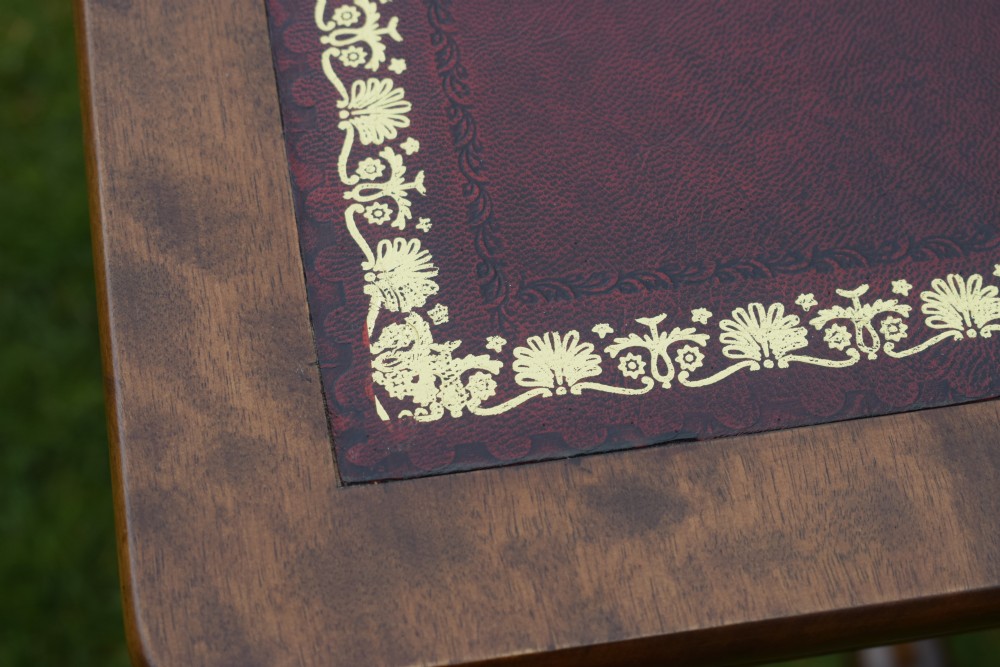 A Victorian mahogany writing table with turned legs, a stretcher base, and an inset red leather top framed with gold leaf tooling. View XIII