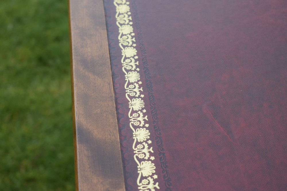 A Victorian mahogany writing table with turned legs, a stretcher base, and an inset red leather top framed with gold leaf tooling. View XIV