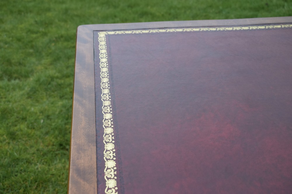 A Victorian mahogany writing table with turned legs, a stretcher base, and an inset red leather top framed with gold leaf tooling. View XV