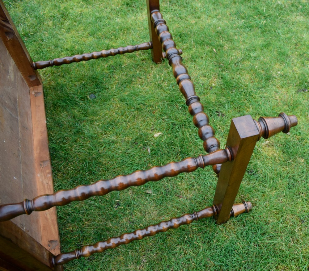A Victorian mahogany writing table with turned legs, a stretcher base, and an inset red leather top framed with gold leaf tooling. View XX
