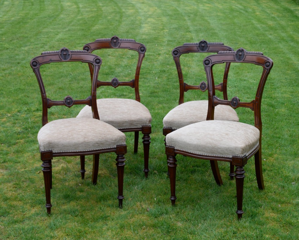 Set of four Victorian walnut dining chairs with carved open backs, turned front legs, and beige fabric upholstered seats. View II