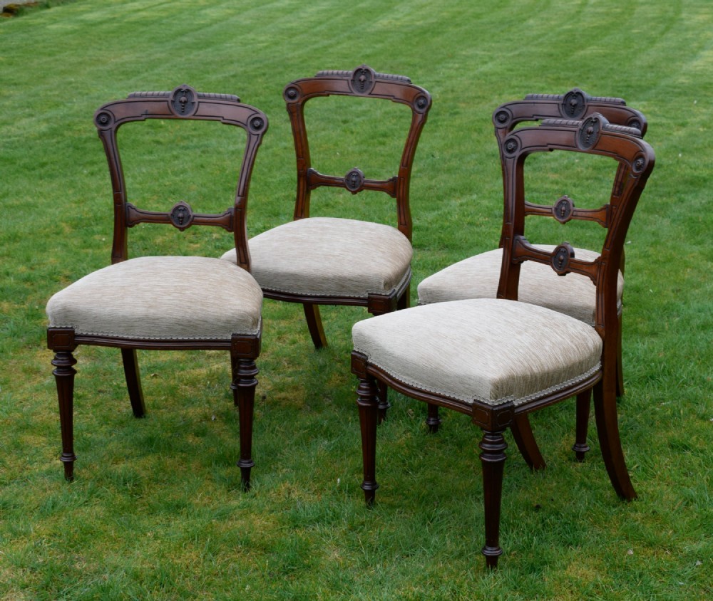 Set of four Victorian walnut dining chairs with carved open backs, turned front legs, and beige fabric upholstered seats. View III