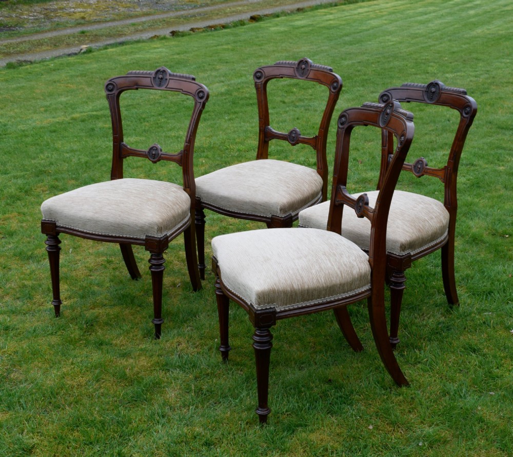 Set of four Victorian walnut dining chairs with carved open backs, turned front legs, and beige fabric upholstered seats. View IV