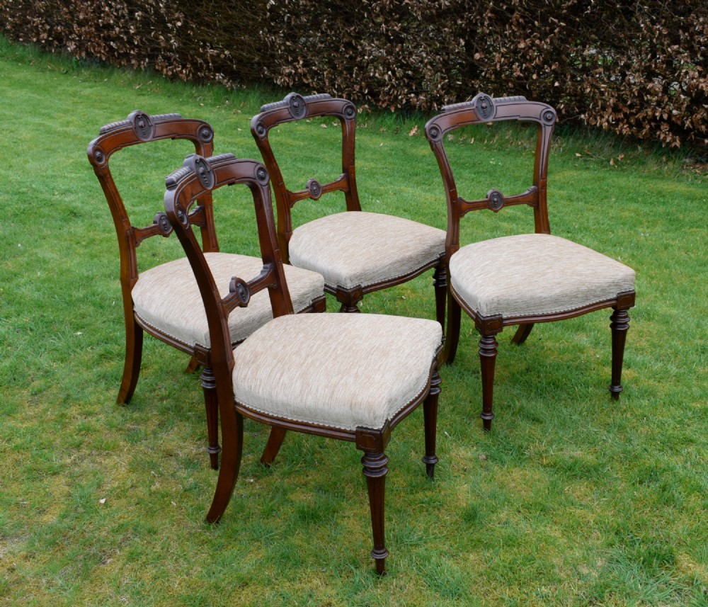 Set of four Victorian walnut dining chairs with carved open backs, turned front legs, and beige fabric upholstered seats. View V