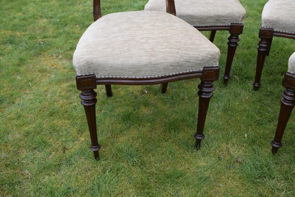 Set of four Victorian walnut dining chairs with carved open backs, turned front legs, and beige fabric upholstered seats. View IX