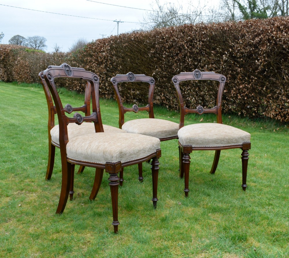 Set of four Victorian walnut dining chairs with carved open backs, turned front legs, and beige fabric upholstered seats. View XII