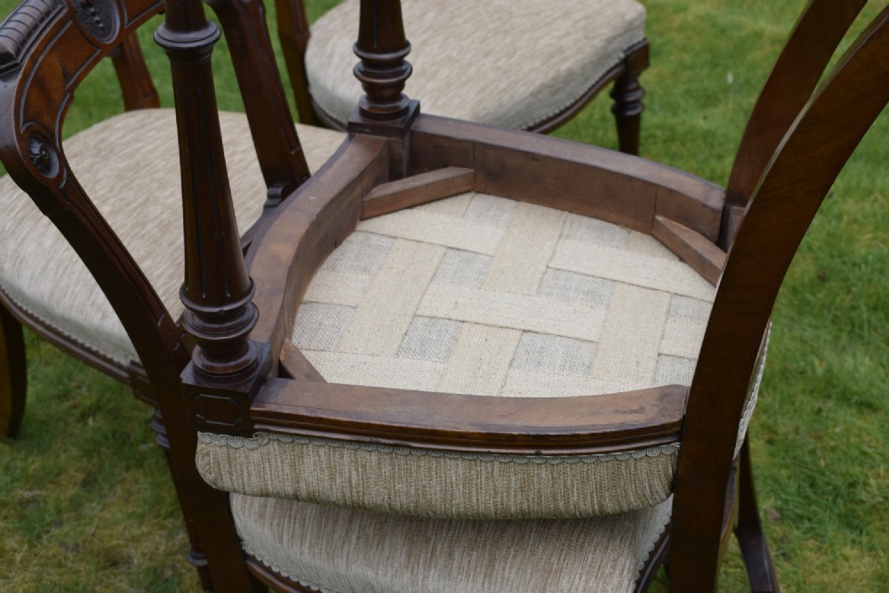 Set of four Victorian walnut dining chairs with carved open backs, turned front legs, and beige fabric upholstered seats. View XIII