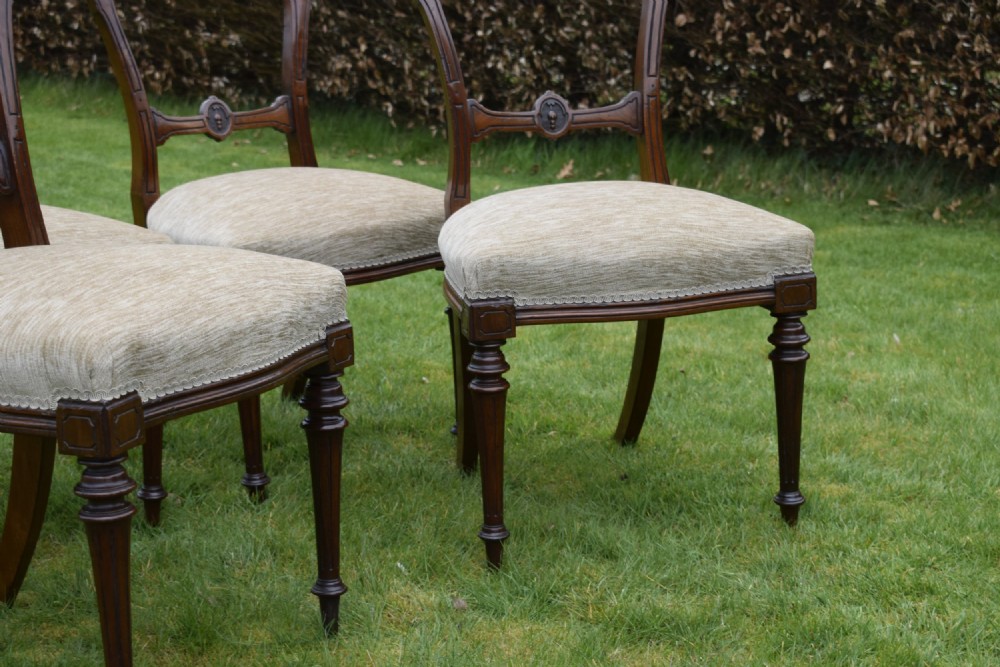 Set of four Victorian walnut dining chairs with carved open backs, turned front legs, and beige fabric upholstered seats. View XIV