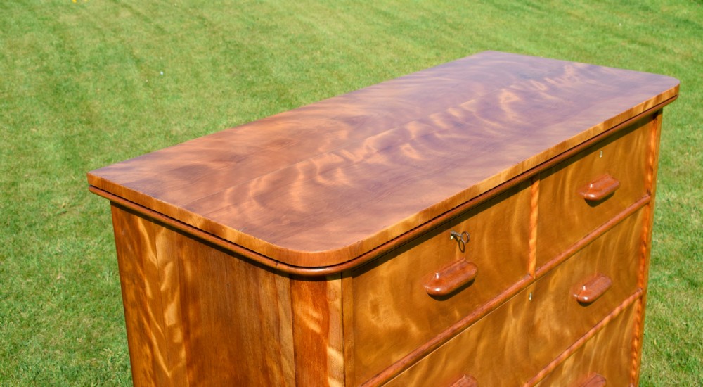Victorian golden birch chest of drawers featuring a two-over-three drawer configuration, rounded corners, integrated timber handles, and a plinth base. View VI