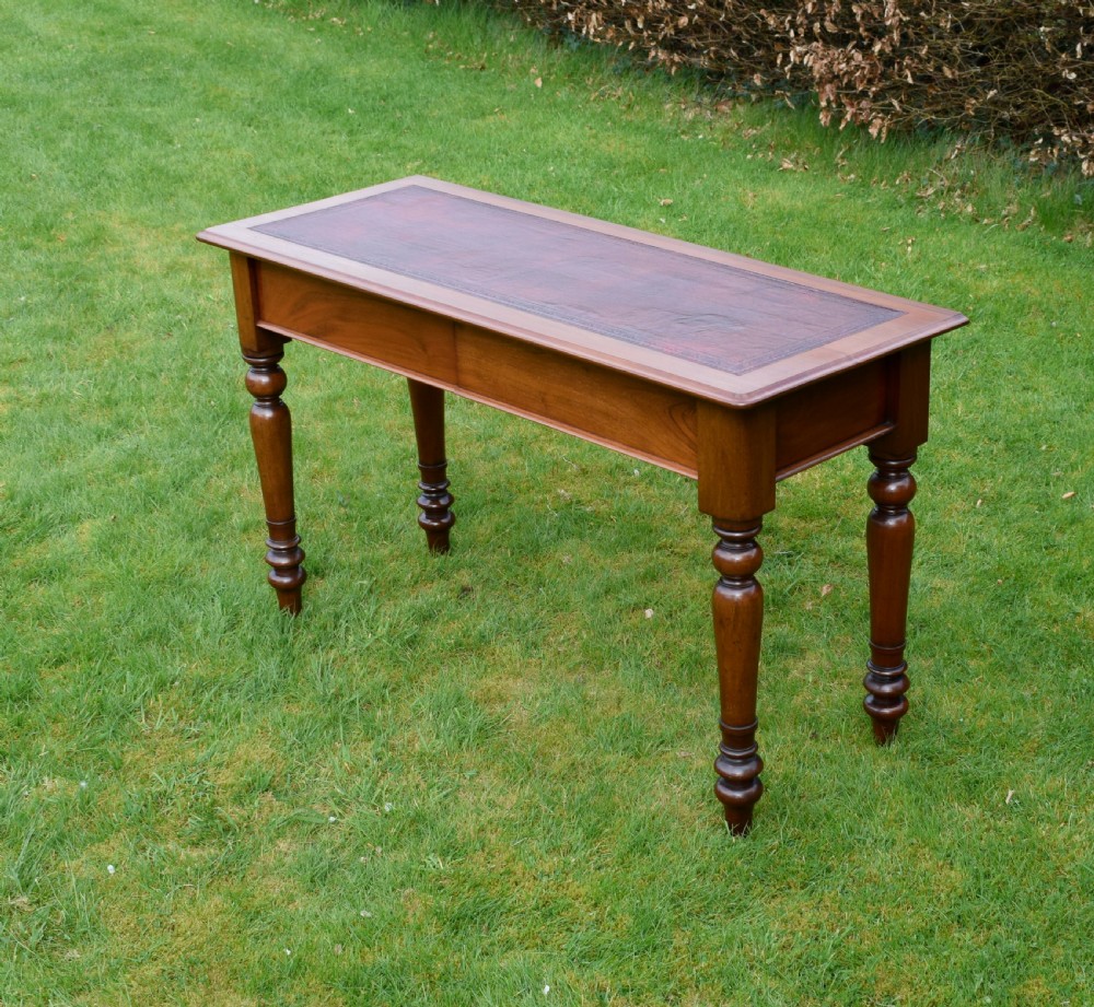 A rectangular Victorian mahogany writing desk featuring a burgundy leather inset top, two frieze drawers, and four turned wooden legs. View IV
