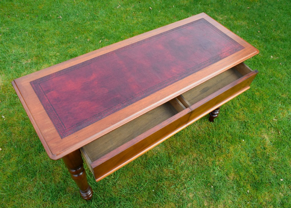 A rectangular Victorian mahogany writing desk featuring a burgundy leather inset top, two frieze drawers, and four turned wooden legs. View XI