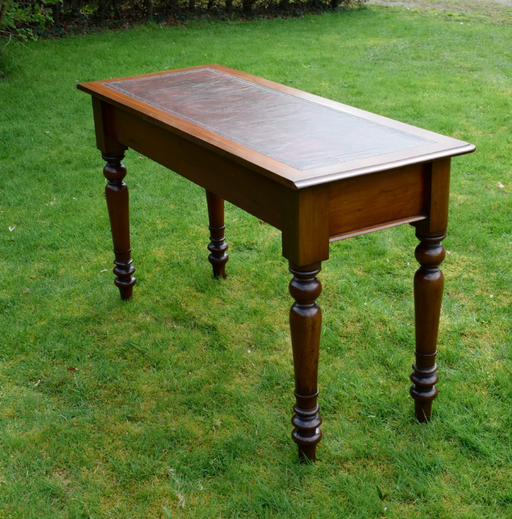 A rectangular Victorian mahogany writing desk featuring a burgundy leather inset top, two frieze drawers, and four turned wooden legs. View XV