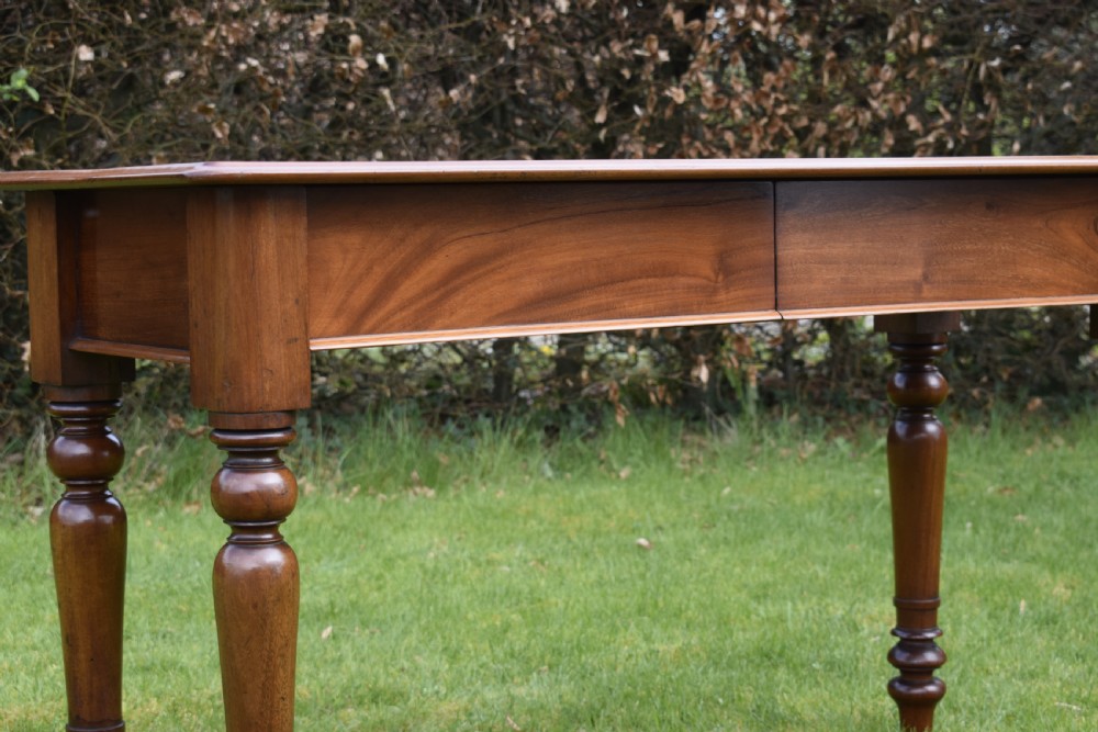 A rectangular Victorian mahogany writing desk featuring a burgundy leather inset top, two frieze drawers, and four turned wooden legs. View XIX