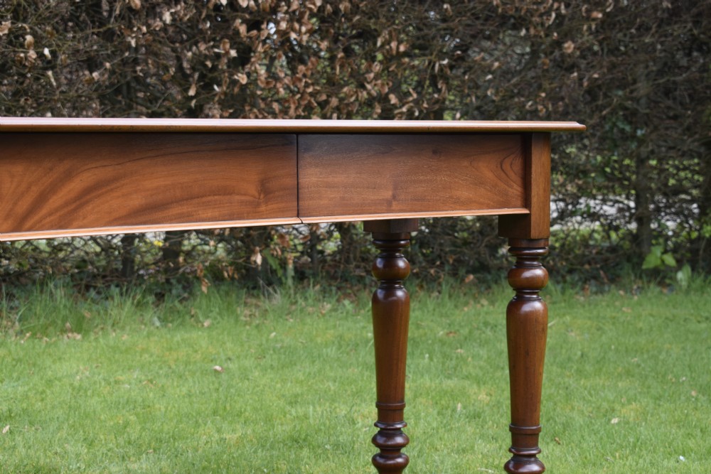 A rectangular Victorian mahogany writing desk featuring a burgundy leather inset top, two frieze drawers, and four turned wooden legs. View XX