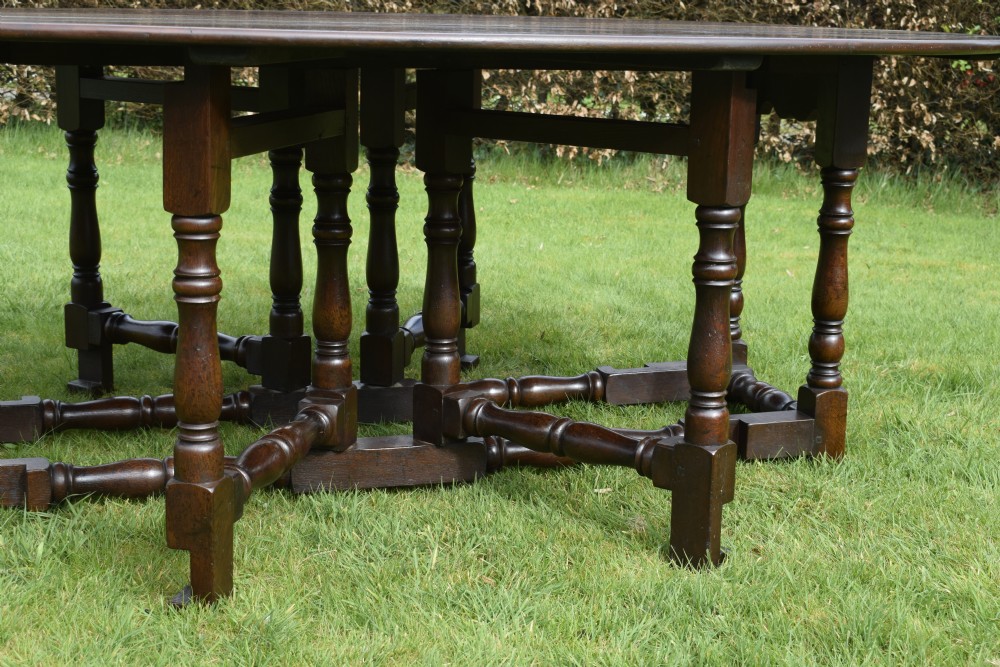 An early twentieth-century dark oak oval wake dining table with two drop-leaf flaps, turned legs, and base stretchers. View III