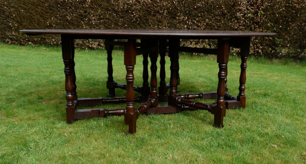 An early twentieth-century dark oak oval wake dining table with two drop-leaf flaps, turned legs, and base stretchers. View V