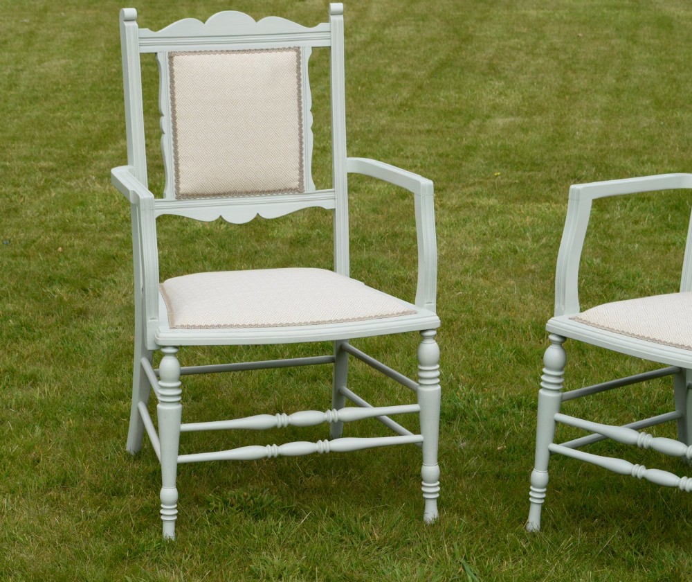 A pair of painted pale green Edwardian open armchairs featuring cream upholstered seats, padded backrest panels, turned front legs, and scalloped top rails. View II