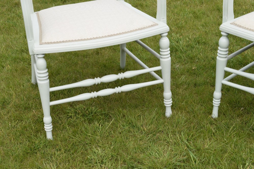 A pair of painted pale green Edwardian open armchairs featuring cream upholstered seats, padded backrest panels, turned front legs, and scalloped top rails. View III