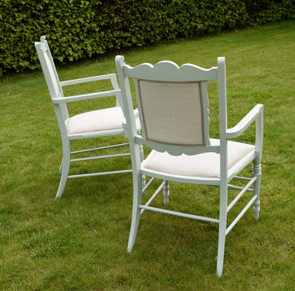 A pair of painted pale green Edwardian open armchairs featuring cream upholstered seats, padded backrest panels, turned front legs, and scalloped top rails. View V