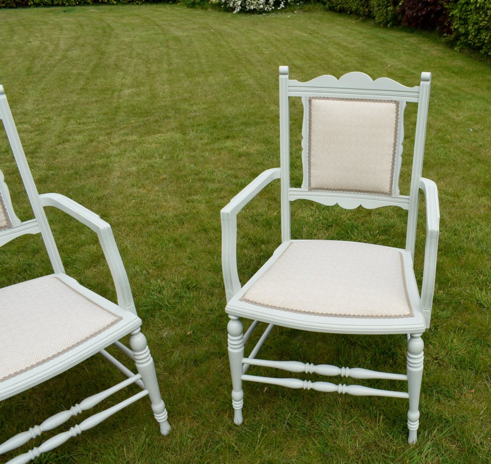 A pair of painted pale green Edwardian open armchairs featuring cream upholstered seats, padded backrest panels, turned front legs, and scalloped top rails. View XII