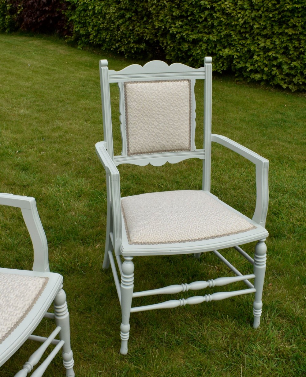 A pair of painted pale green Edwardian open armchairs featuring cream upholstered seats, padded backrest panels, turned front legs, and scalloped top rails. View XIV