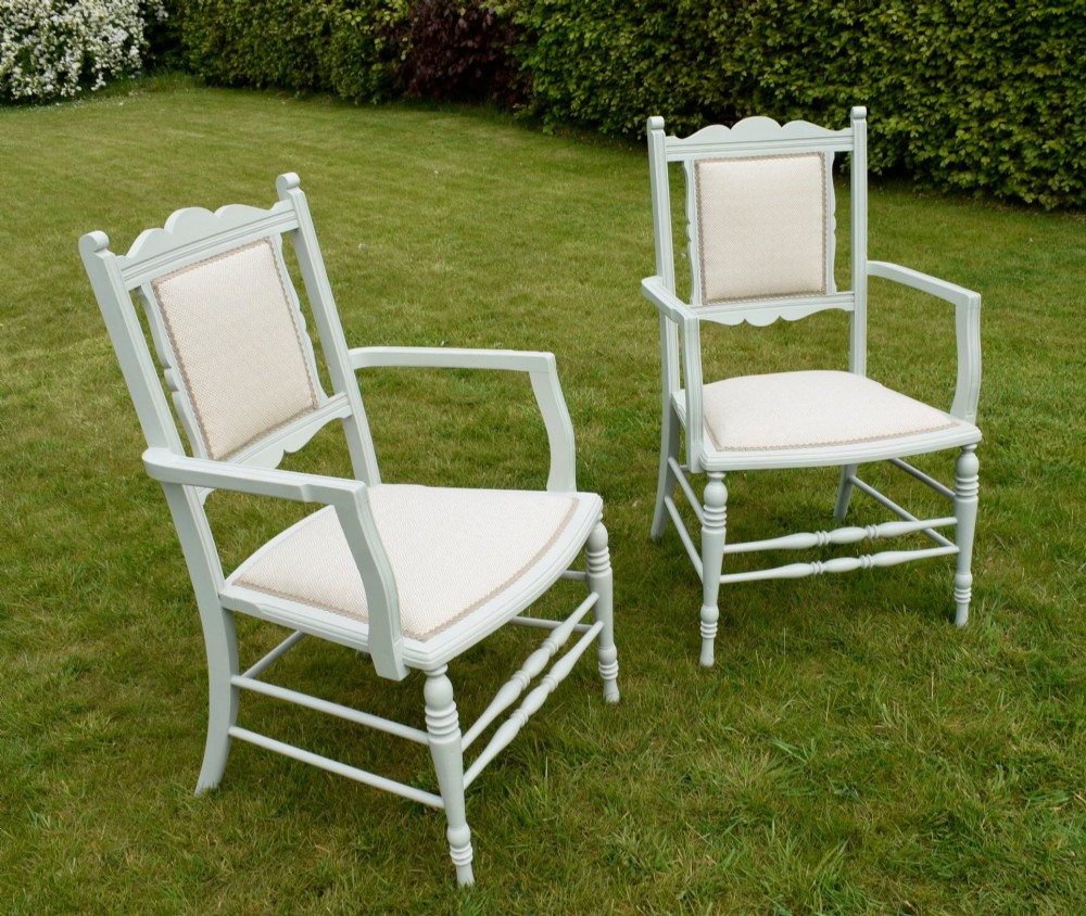 A pair of painted pale green Edwardian open armchairs featuring cream upholstered seats, padded backrest panels, turned front legs, and scalloped top rails. View XV