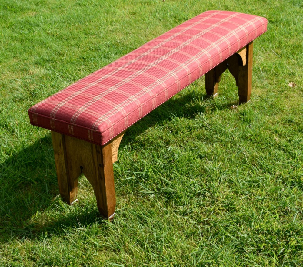 An oak window bench featuring a padded red tartan upholstered seat supported by solid oak legs with Gothic arch cut-out details. View XI