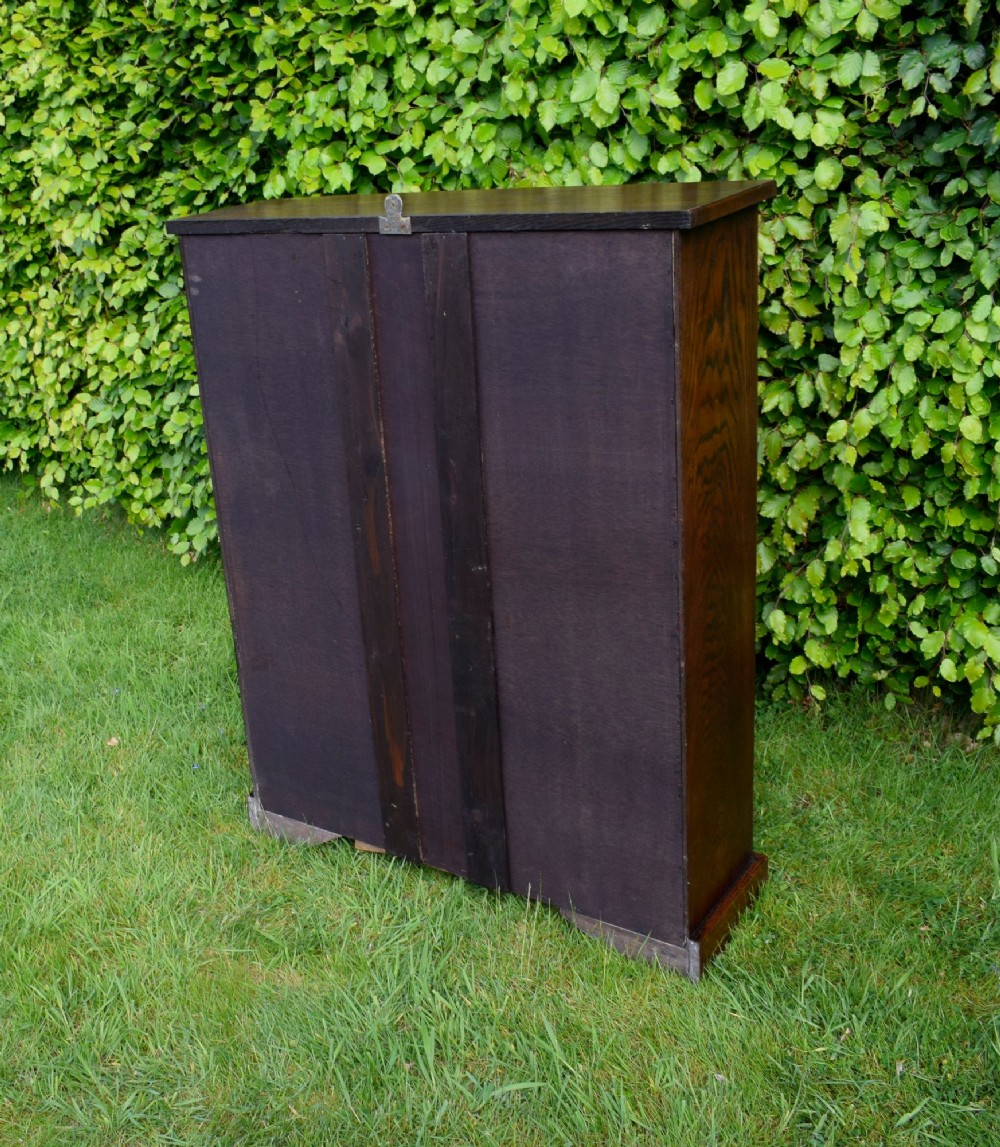 A dark oak glazed cabinet featuring a single glass door opening to internal shelving backed with a neutral patterned fabric lining. View VII